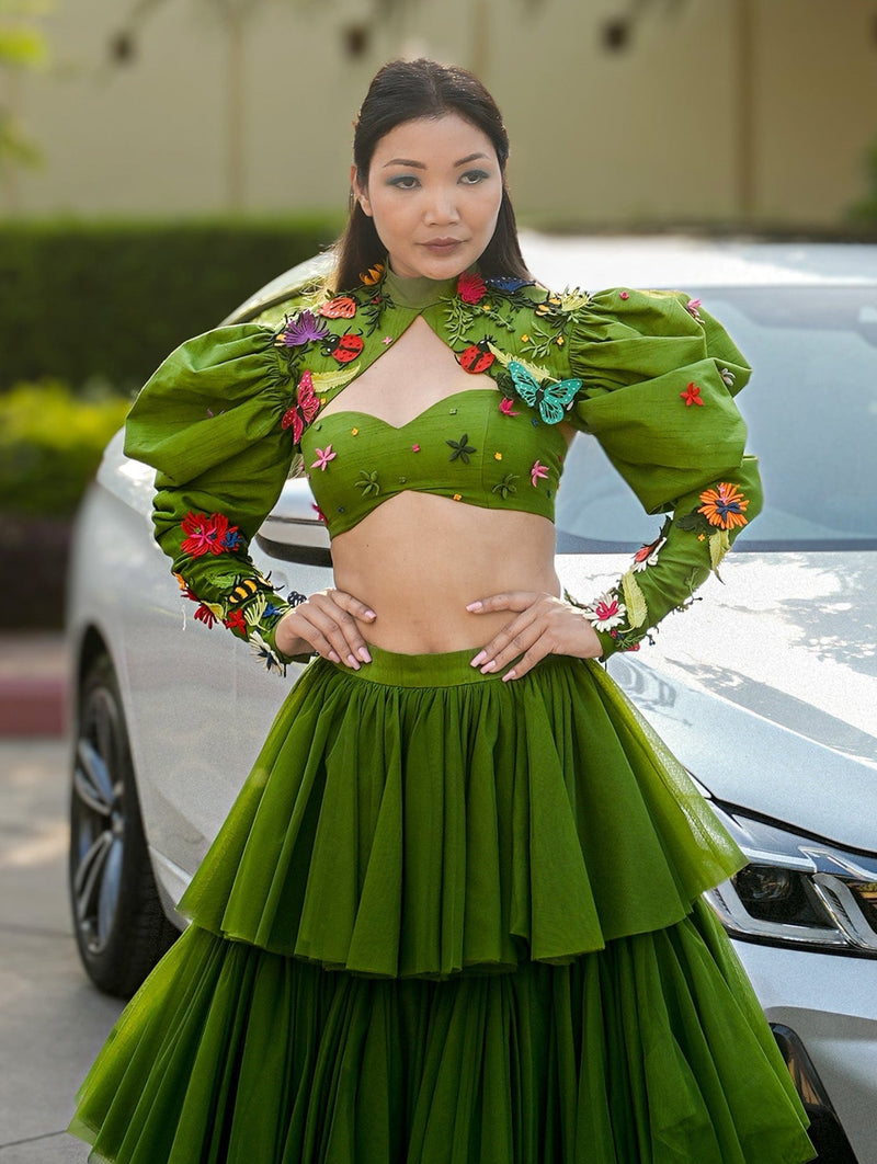 Woman in a green traditional outfit standing next to a BMW car