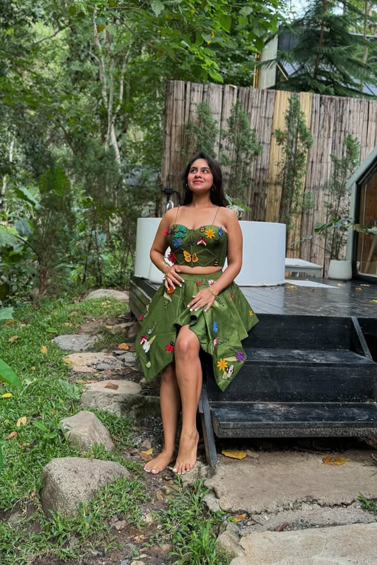 Pavitra Kaur in Modo Caldo green fit-and-flare corset top with asymmetric skirt and fringed cape, featuring signature applique embroidery for festive and formal wear