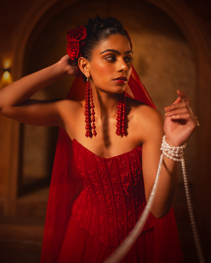 ISHQe campaign: red corset top with long beaded tassel earrings and a red rose in the hair