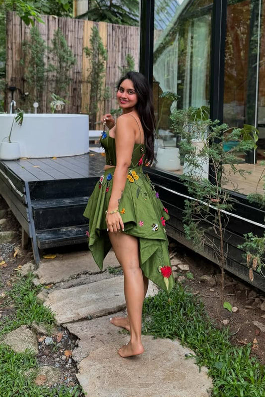 Pavitra Kaur in Modo Caldo green fit-and-flare corset top with asymmetric skirt and fringed cape, featuring signature applique embroidery for festive and formal wear