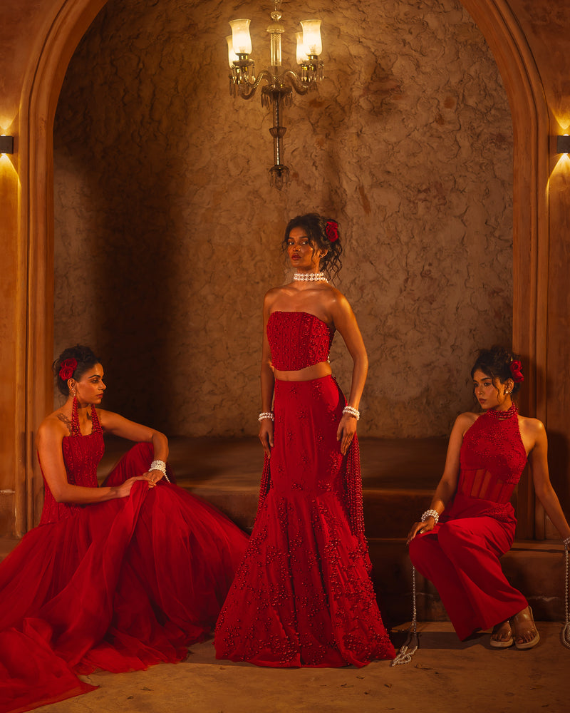 ISHQe campaign: three models in red lehengas and corset sets under a chandelier