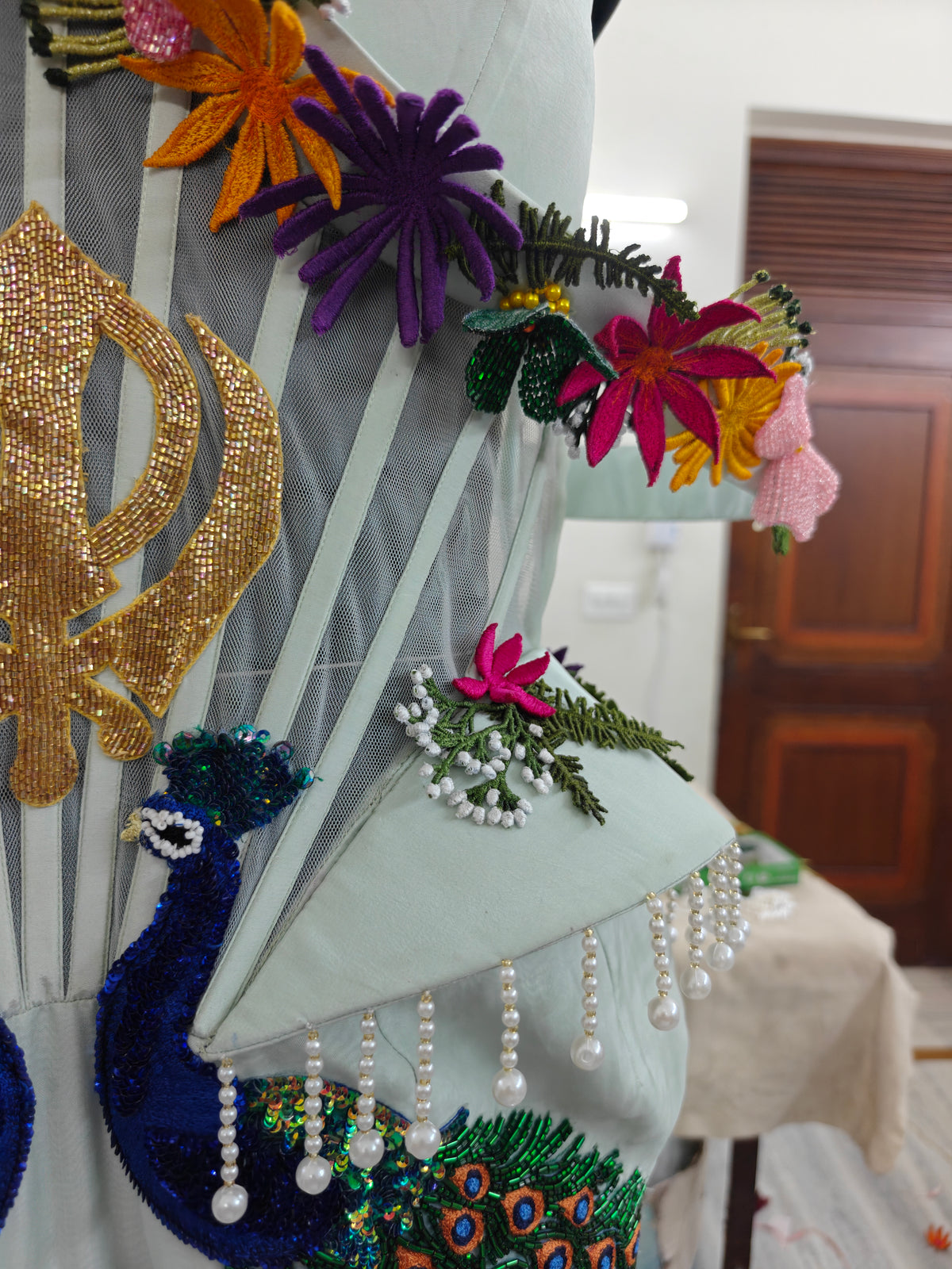 Natkhat Zindagi in progress: gold Khanda, peacock and flower embroideries pinned to a dress form