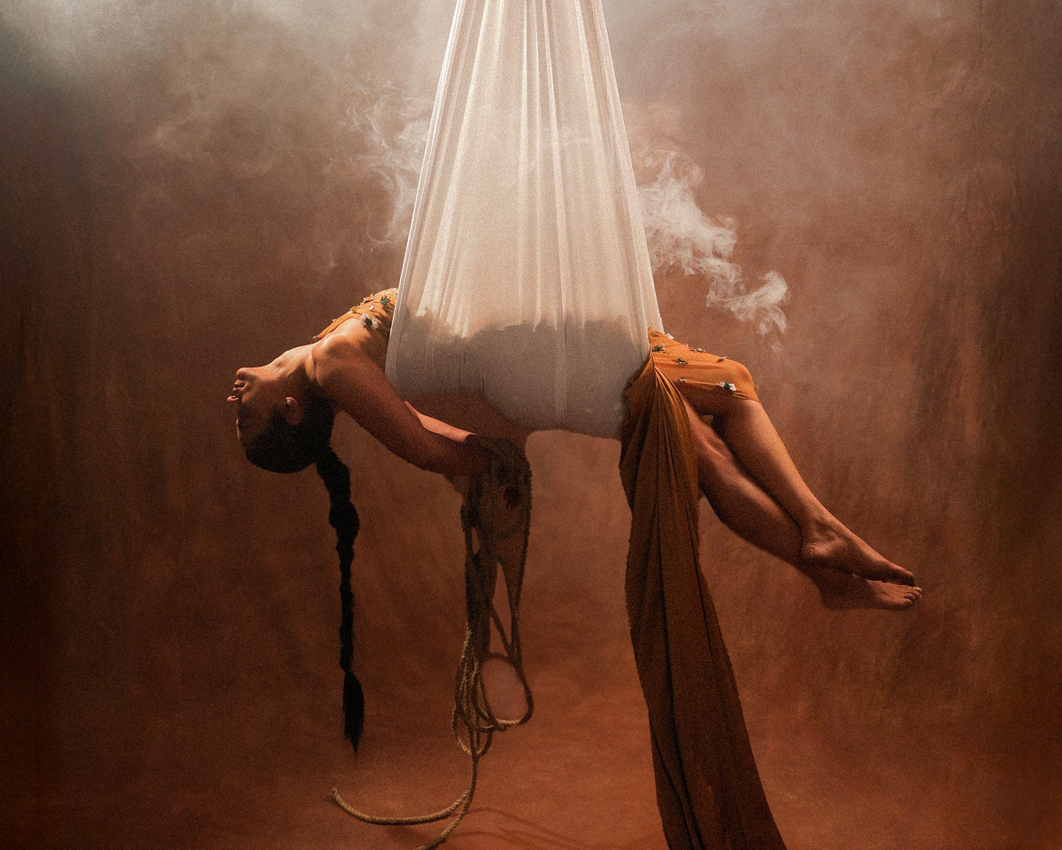 Hope campaign: model in a copper brown gown lying in a white hanging hammock