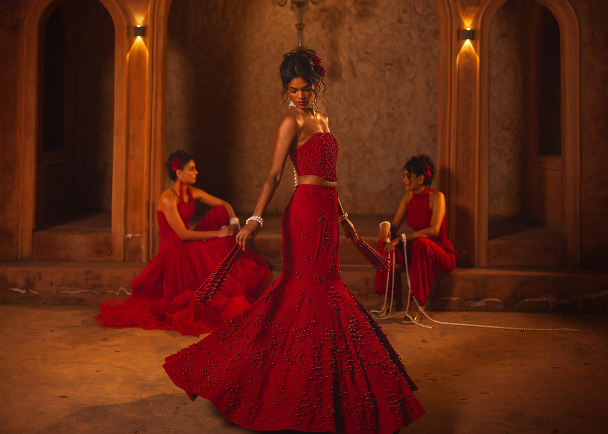 ISHQe campaign: red corset mermaid gown and two red lehengas with pearl embroidery in a palace corridor