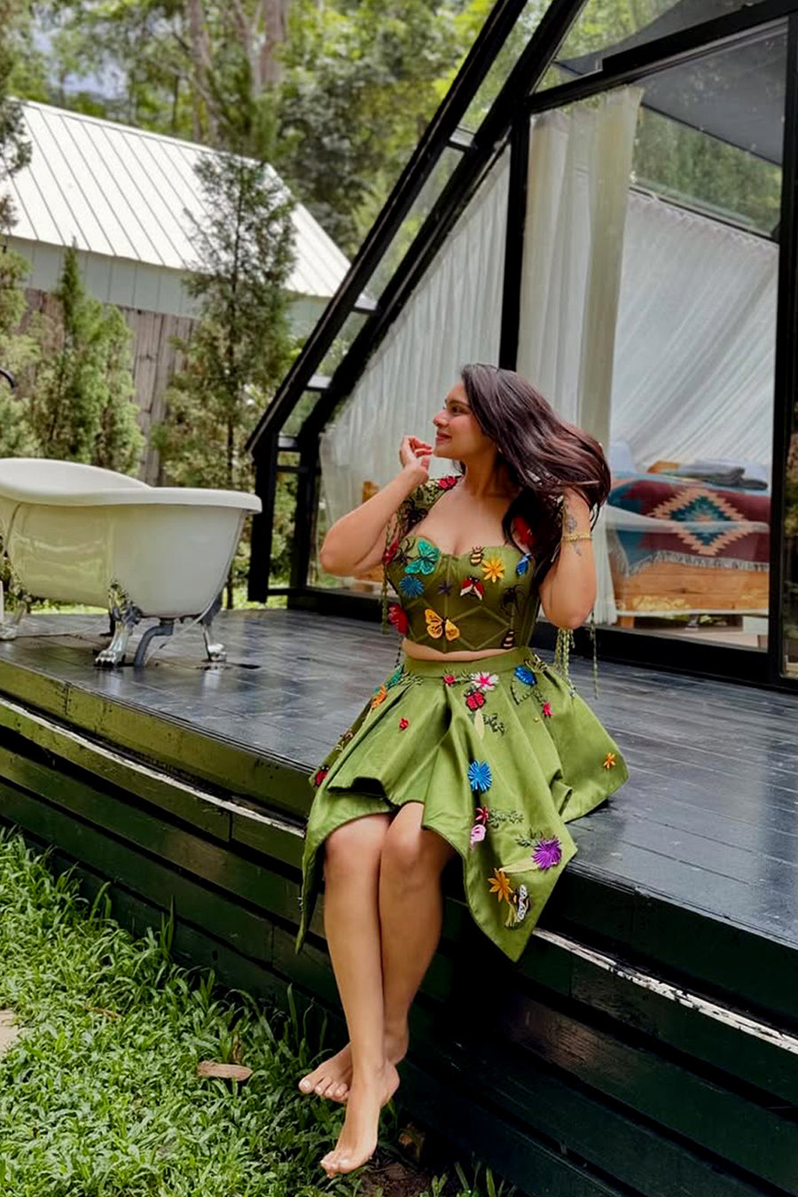 Pavitra Kaur in  Modo Caldo green fit-and-flare corset top with asymmetric skirt and fringed cape, featuring signature applique embroidery for festive and formal wear