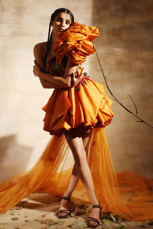 Short orange dress gathered into a rounded hem, net trail spreading behind